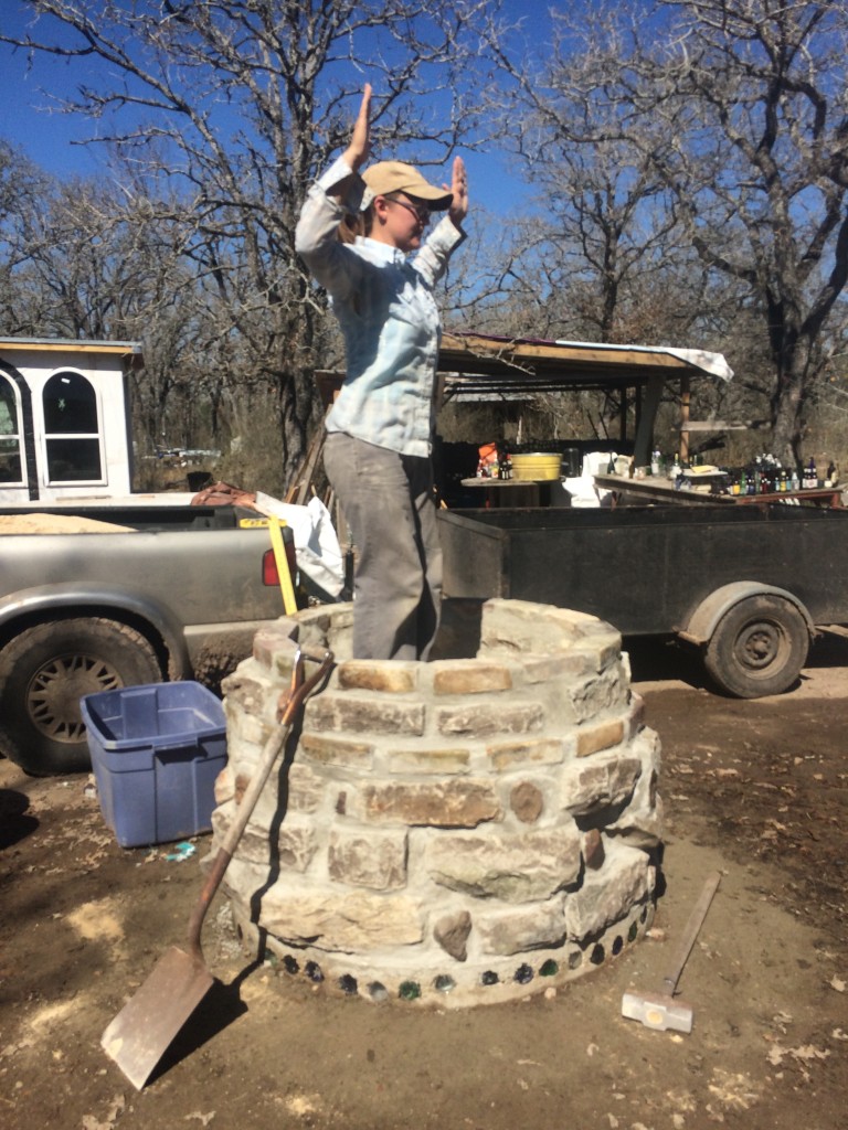 Kristin does the Tamping Dance - we filled the lower base with a mix of sand and crushed glass (necks left over from bottle bricks used in the ongoing bottle-house construction, visible in the background)