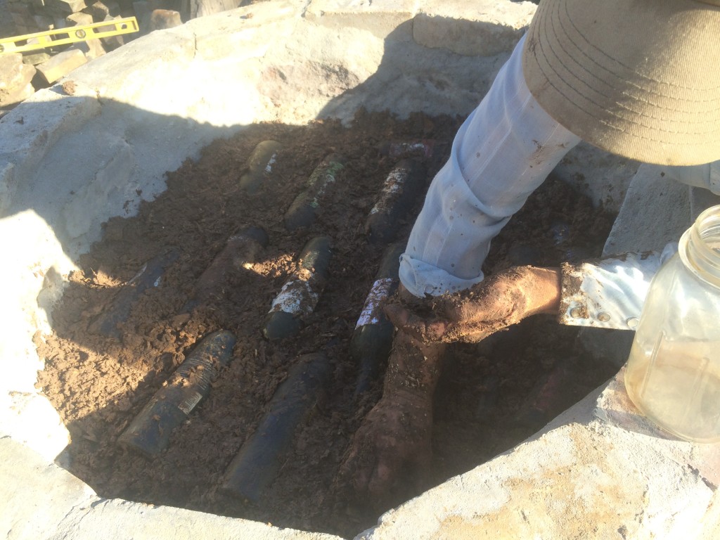 wine bottle layer being filled in with clay slip/wood shaving insulation mud