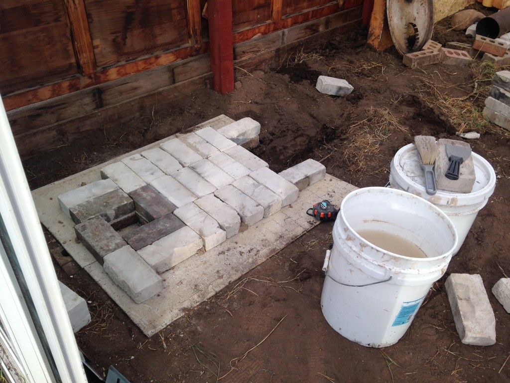 laying the base layer, with pits for ash cleanouts. White bricks insulate against heat loss, keeping temperatures high for the heat riser, where even the smoke will burn up