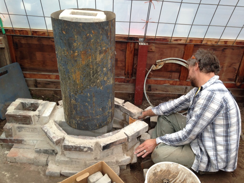 although the heat riser was made of insulative fire brick, I realized it would be even better with more insulation - so I cut apart an old water heater and added it - later filling the space between it and the riser with perlite insulation mixed with clay slip.