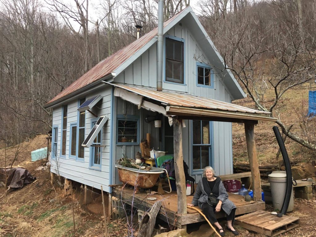 Jacqueline in front of Pat's off-grid homestead